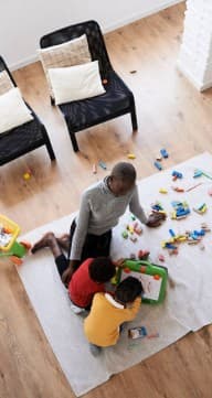 Un tuteur joue avec des enfants sur un tapis d'activités